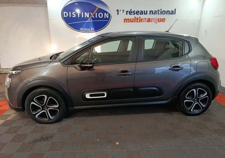 Vue de profil côté gauche d'une Citroën C3 2024 gris foncé avec protections latérales noires et jantes stylisées.