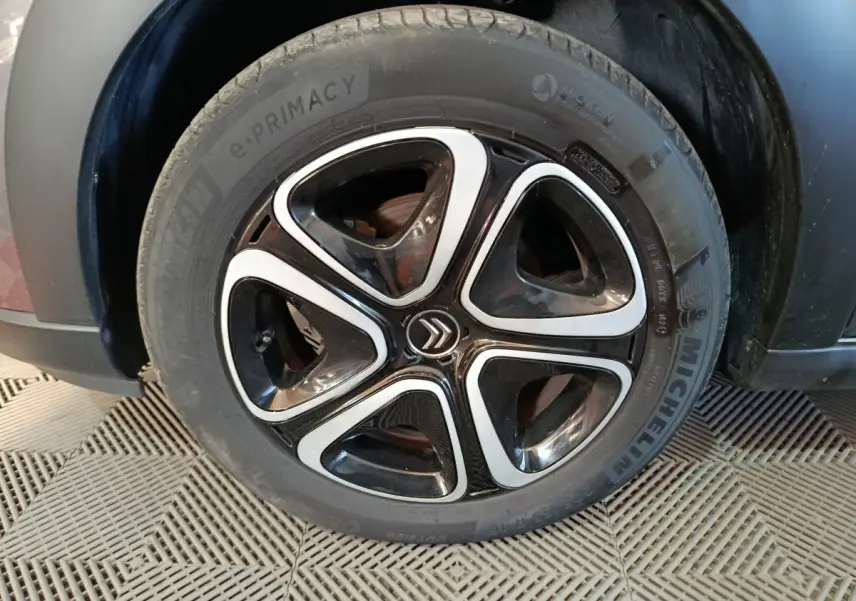 Gros plan sur la roue avant droite d'une Citroën C3 gris foncé avec jante noire et inserts argentés distinctifs.