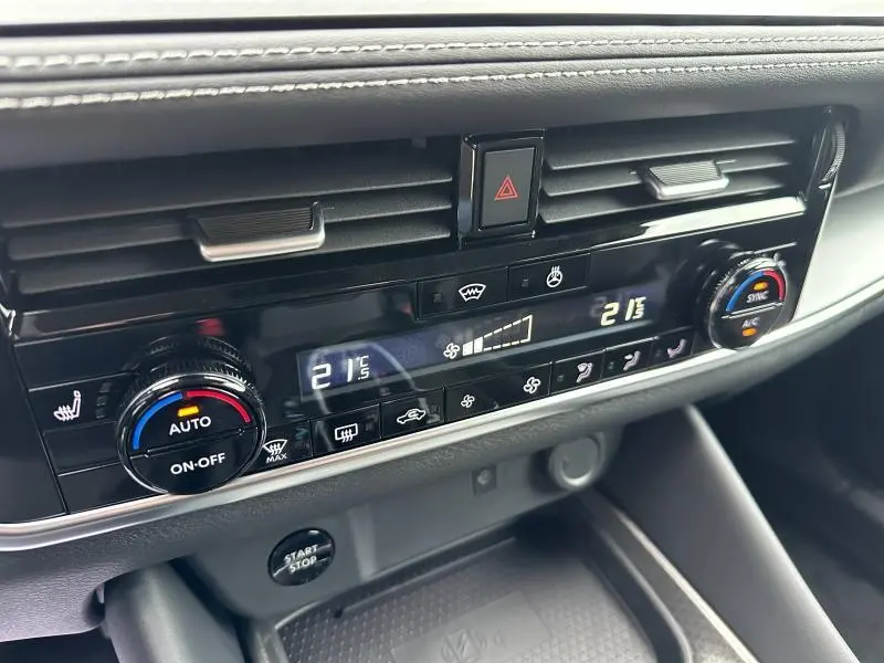 Vue rapprochée de la console centrale du Nissan Qashqai Hybrid e-POWER 2025, avec commandes climatisation digitales et boutons noirs.