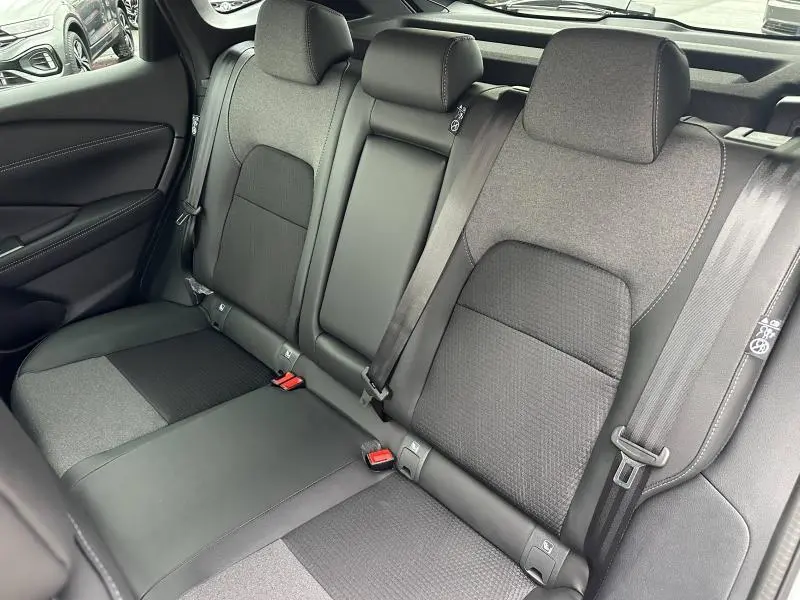 Vue intérieure des sièges arrière du Nissan Qashqai Hybrid e-POWER 2025, tissu noir avec ceintures de sécurité visibles.