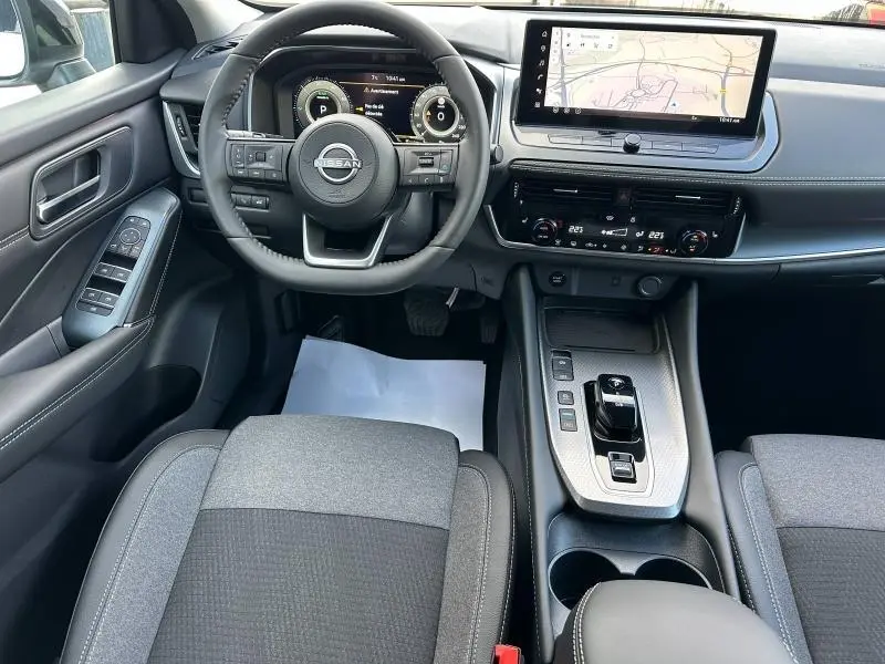 Vue intérieure du Nissan Qashqai Hybrid e-POWER 2025 montrant le tableau de bord, volant multifonction et écran tactile central.