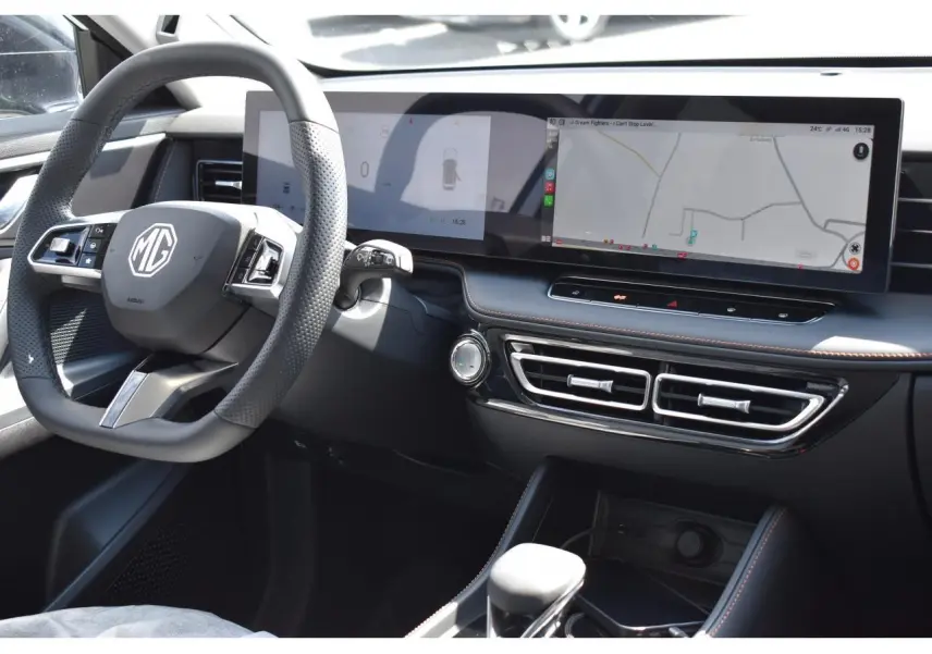 Vue intérieure côté conducteur du MG Motor EHS blanc 2026, avec volant multifonction et écran tactile panoramique.