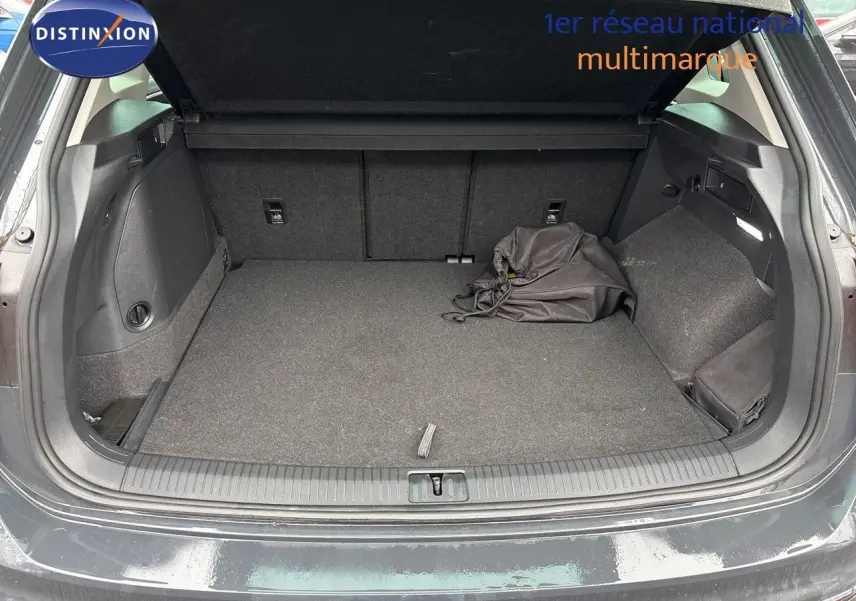 Coffre ouvert d'un Volkswagen Tiguan gris lunaire 2022, montrant un espace de chargement propre avec sac noir.
