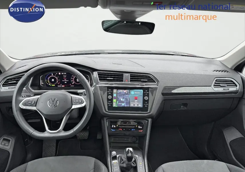 Vue intérieure avant du Volkswagen Tiguan gris lunaire 2022, tableau de bord moderne avec écran tactile et volant multifonction.