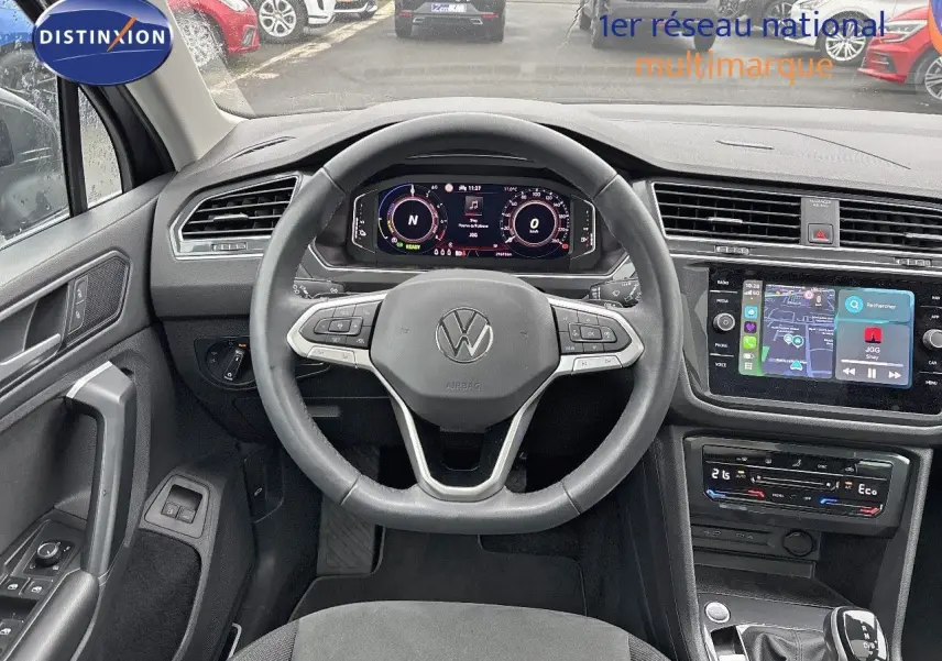Vue intérieure frontale du tableau de bord et volant du Volkswagen Tiguan 1.4 E-HYBRID gris lunaire avec écran tactile et commandes au volant.