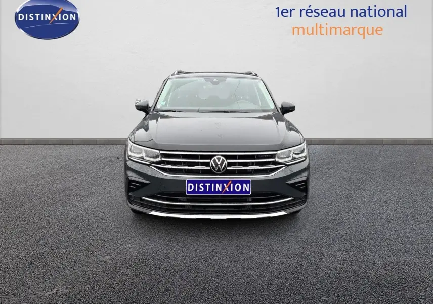 Vue frontale d'un Volkswagen Tiguan gris lunaire 2022 hybride rechargeable avec calandre chromée et logo VW visible.