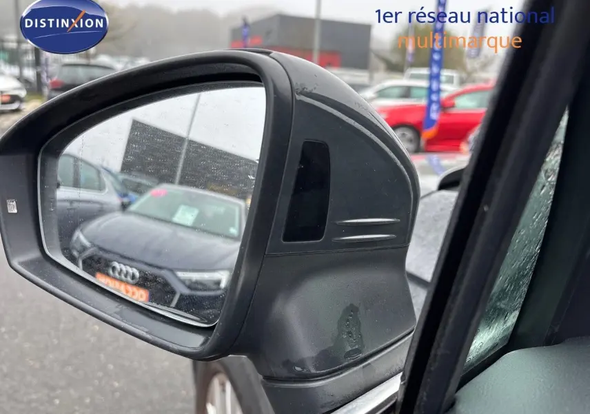 Rétroviseur extérieur gauche du Volkswagen Tiguan gris lunaire, avec reflet d'une Audi noire en arrière-plan.