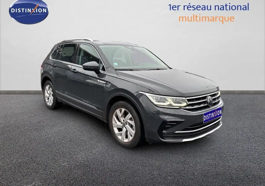 Volkswagen Tiguan 1.4 E-Hybrid gris lunaire vu en 3/4 avant droit avec phares LED allumés sur fond neutre.