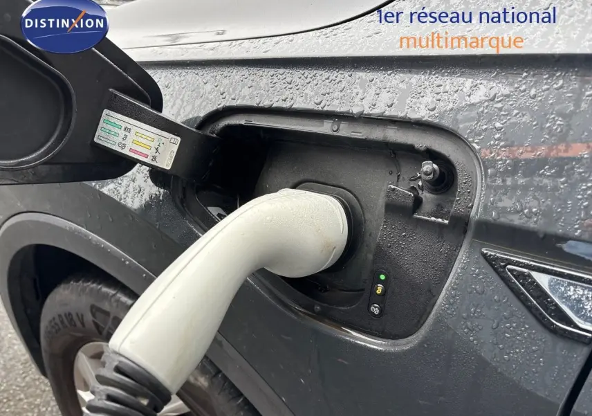 Prise de recharge en gros plan sur le côté gauche d'un Volkswagen Tiguan gris lunaire hybride rechargeable sous la pluie.