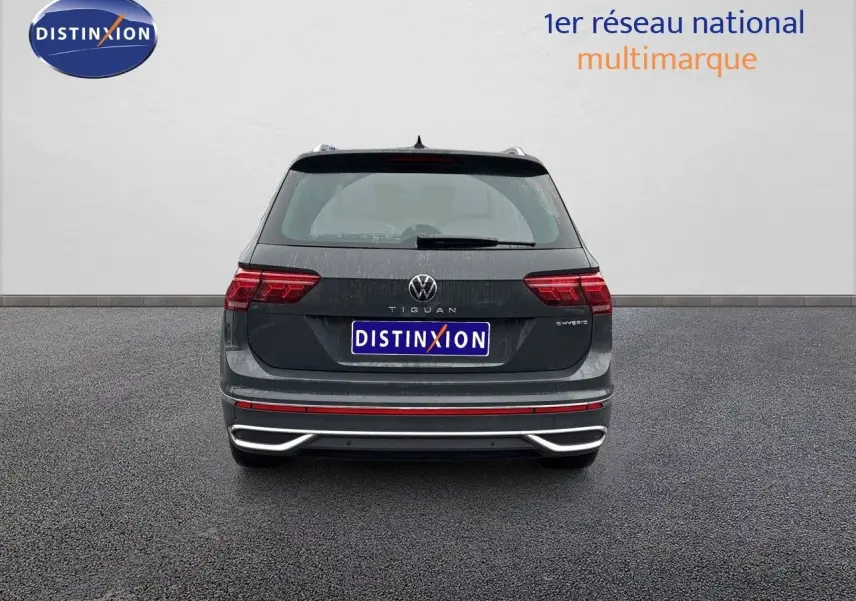 Vue arrière d'un Volkswagen Tiguan gris lunaire hybride rechargeable avec feux LED et logo distinctif visible.