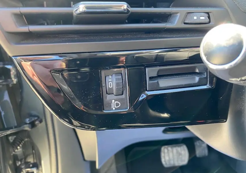 Gros plan sur la commande de réglage des phares côté gauche du tableau de bord intérieur d'une Citroën C4 Picasso gris shark.
