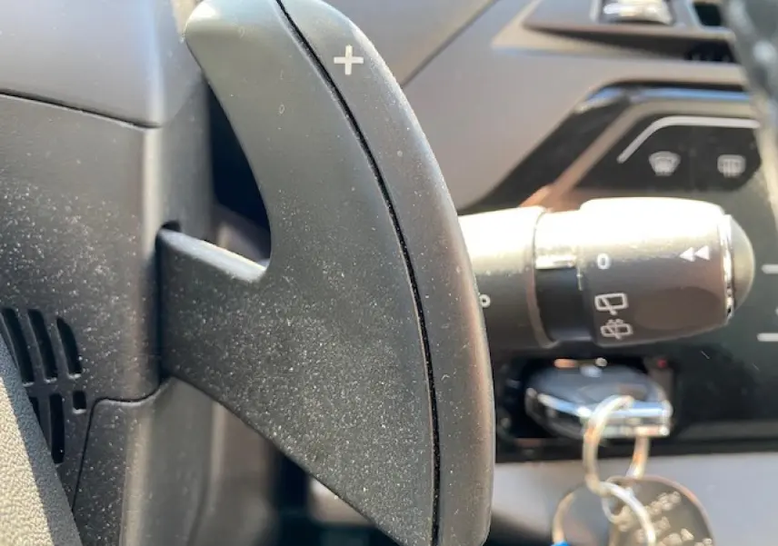 Gros plan sur la palette de commande + au volant noir du Citroën C4 Picasso 2016, avec clé insérée au contacteur.