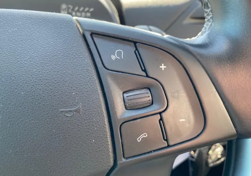 Gros plan sur les commandes vocales et volume au volant cuir noir du Citroën C4 Picasso gris Shark de 2016.