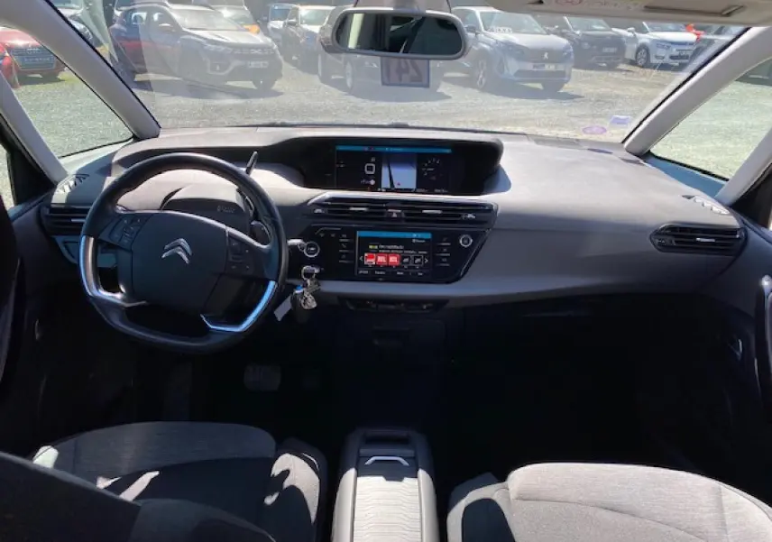 Vue intérieure avant du Citroën C4 Picasso 2016, tableau de bord gris avec écran tactile et volant multifonction.
