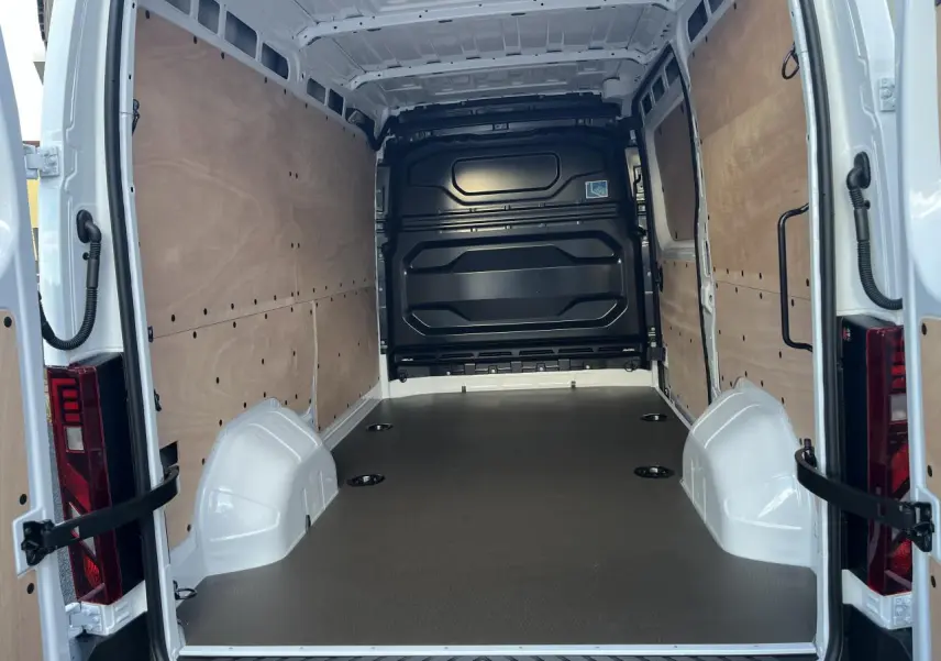 Vue arrière intérieure du Renault Master blanc 2025 montrant l'espace de chargement avec plancher bois et parois tôlées.