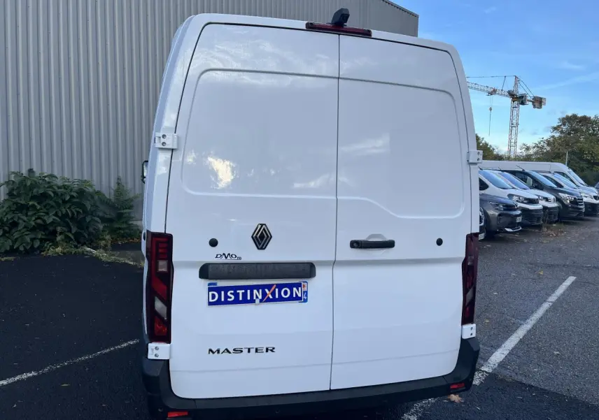 Vue arrière d’un utilitaire Renault Master blanc avec portes arrière tôlées et logo noir sur parking.