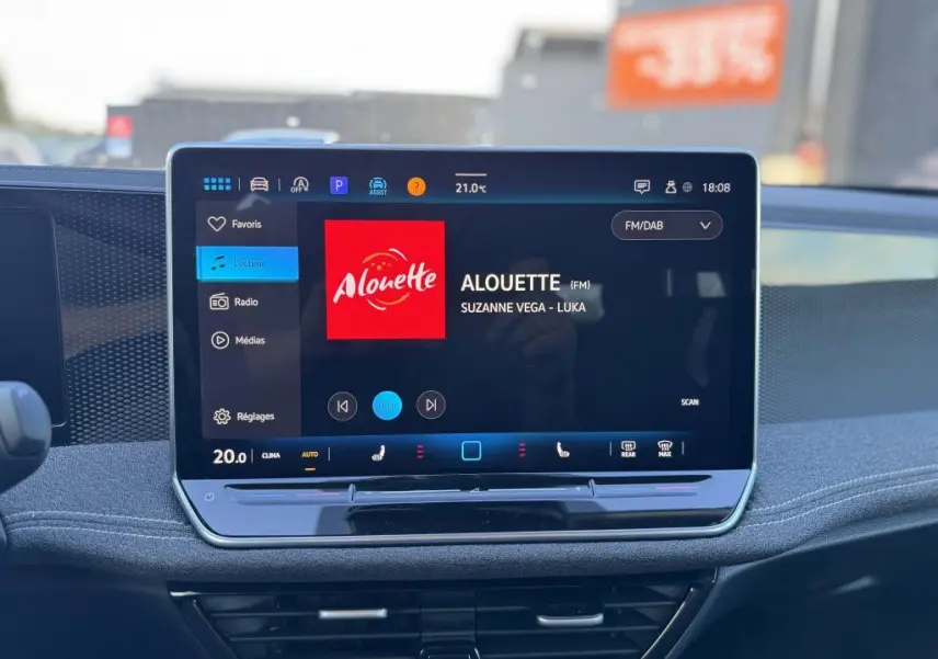 Écran tactile 12,9" du tableau de bord d'une Volkswagen Passat SW noire, affichant la radio Alouette.