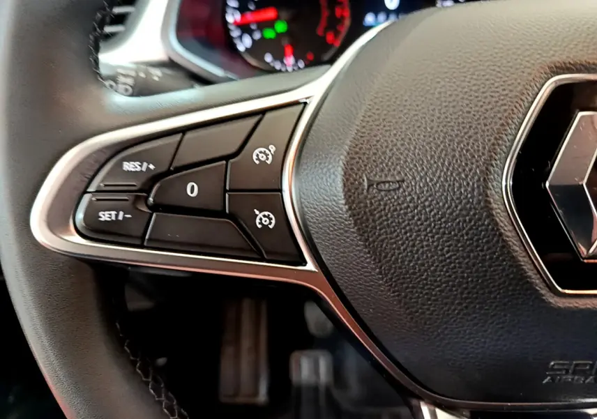 Gros plan sur le volant noir du Renault Captur Business TCe 90 2021, avec commandes de régulateur de vitesse visibles à gauche.