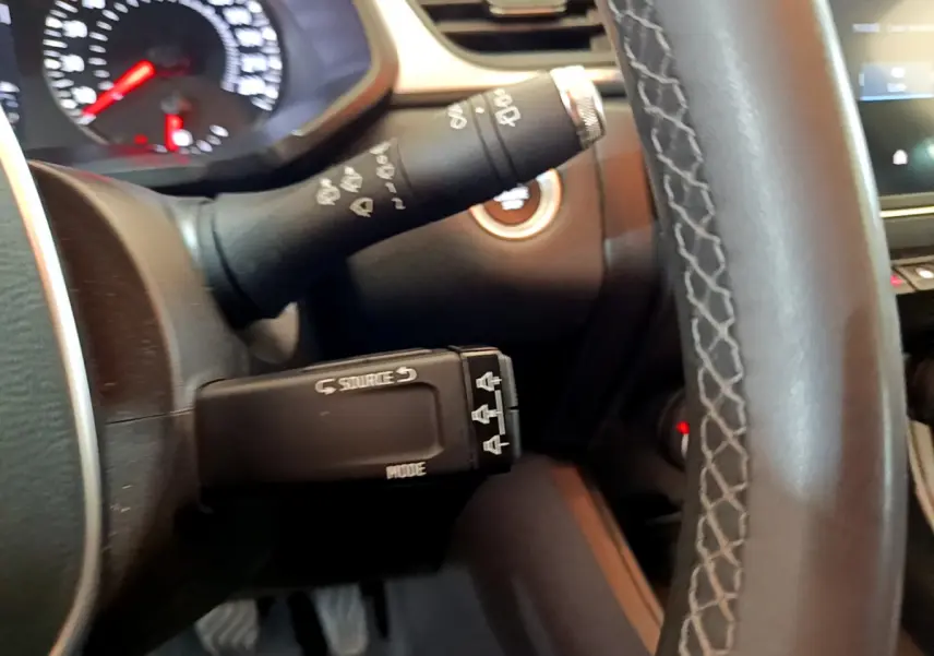 Gros plan sur le commodo gauche et volant noir du Renault Captur Business TCe 90 2021, avec tableau de bord partiellement visible.