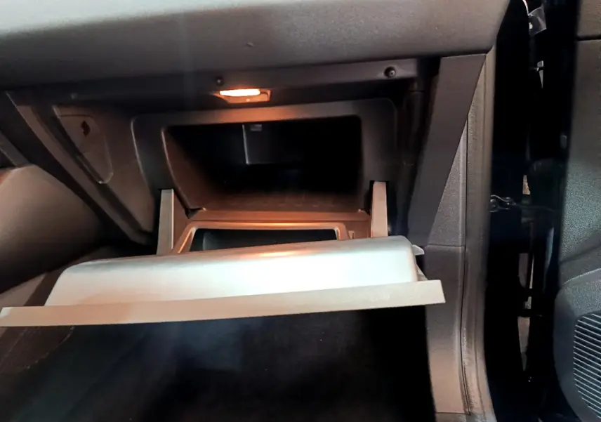 Intérieur du Renault Captur Business 2021, vue sur la boîte à gants ouverte côté passager, éclairage intérieur allumé.