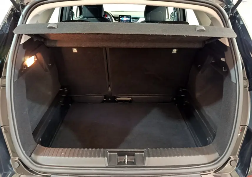 Coffre ouvert noir du Renault Captur Business TCe 90 2021, vue arrière avec tablette de cachette relevée.
