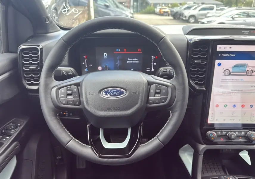 Vue intérieure centrée sur le volant du Ford Ranger 2025 noir agate avec tableau de bord digital et écran tactile vertical.