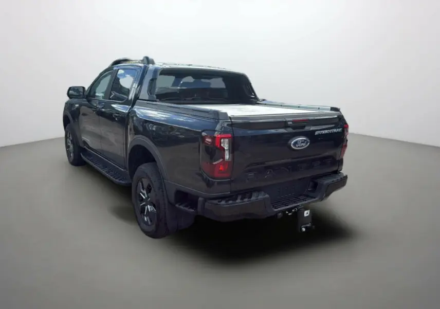 Vue 3/4 arrière du Ford Ranger 2025 noir agate avec benne couverte et badge Stormtrak visible sur la porte de coffre.