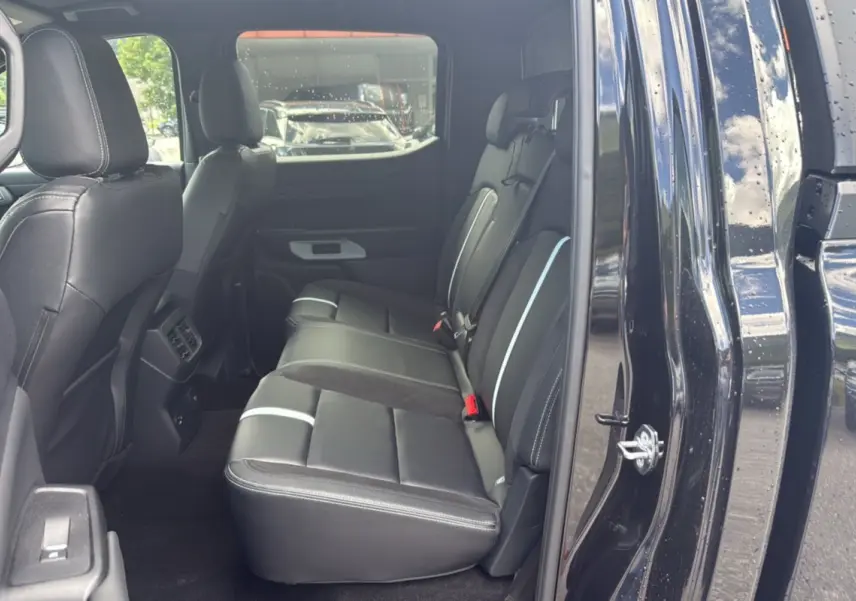 Vue intérieure arrière côté droit du Ford Ranger 2025 noir agate, montrant les sièges en cuir noir avec surpiqûres blanches.