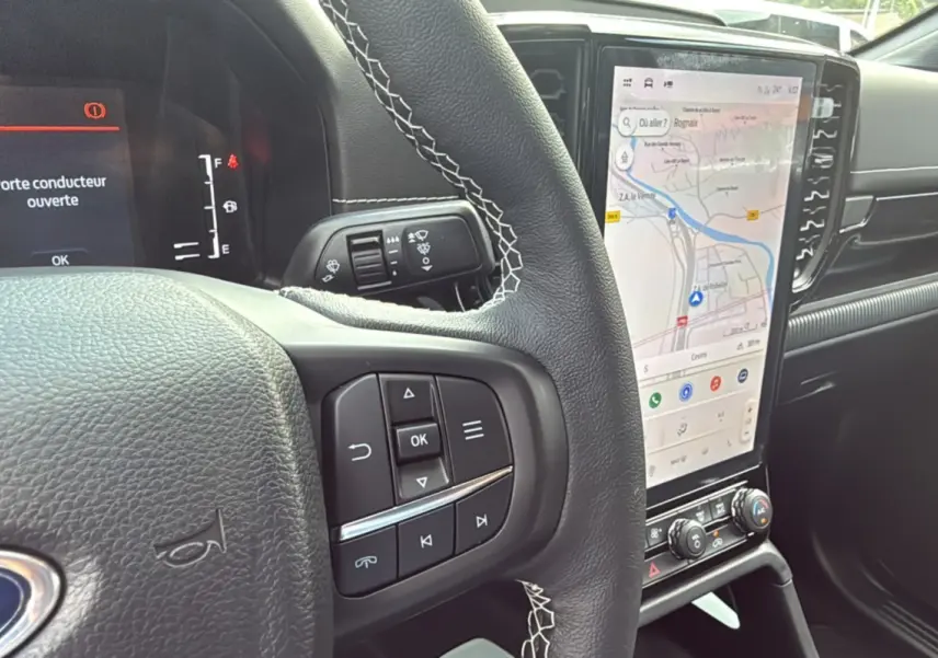 Vue rapprochée du volant et de l'écran tactile du Ford Ranger 2025 noir agate, affichant la navigation et le tableau de bord digital.