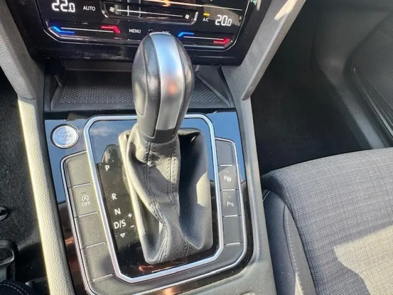 Gros plan sur le levier de vitesses automatique noir et la console centrale brillante d'une Volkswagen Passat SW gris manganèse.