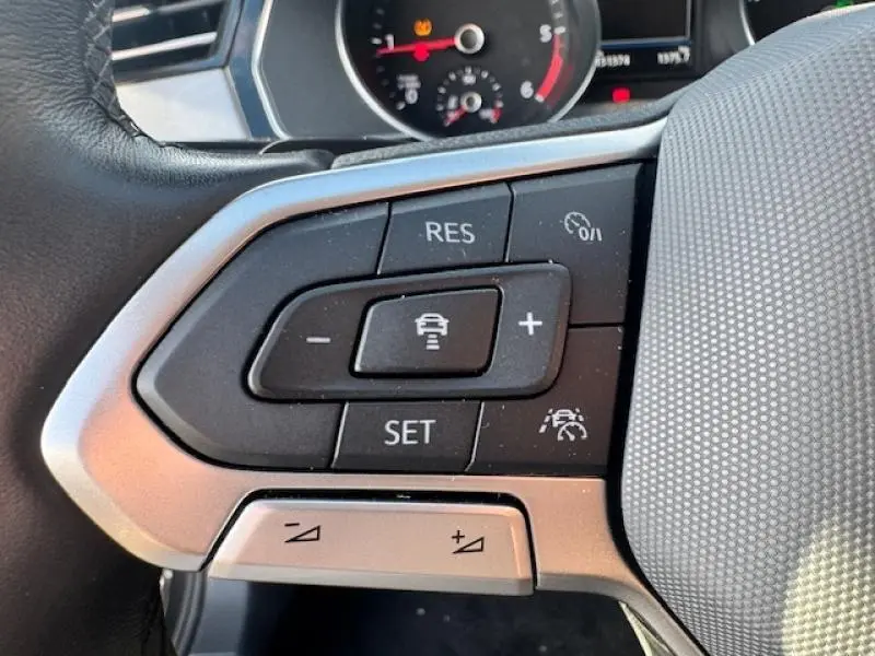 Gros plan sur les commandes multifonctions à gauche du volant cuir de la Volkswagen Passat SW gris manganèse.