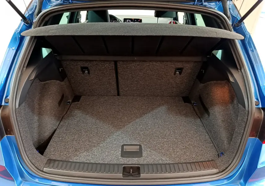 Coffre ouvert vu de l'arrière du SEAT Arona bleu 2022, espace de chargement vide et tapis gris.