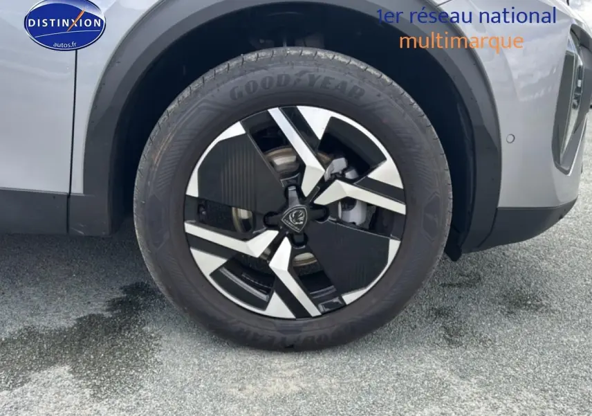 Gros plan sur la roue avant droite avec jante alu bicolore du Peugeot 2008 gris Artense.