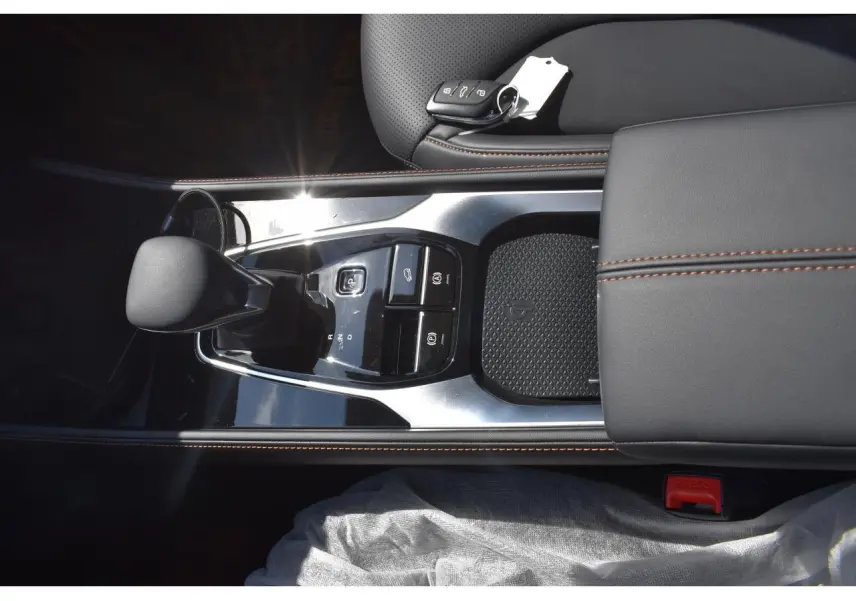 Vue plongeante sur la console centrale noire du MG Motor EHS 1.5 Hybrid+ avec levier de vitesses et surpiqûres marron.