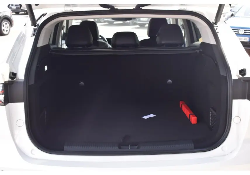 Coffre ouvert d’un MG Motor EHS blanc, vue arrière montrant l’espace de chargement vide avec un triangle de sécurité rouge.