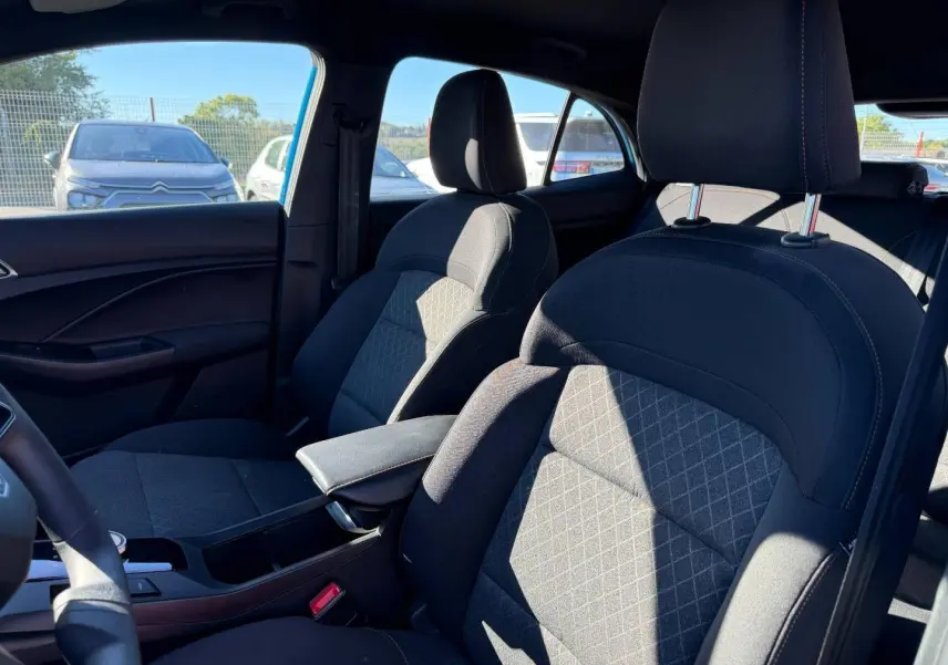 Vue intérieure côté droit du MG3 1.5 Hybrid+ 195ch Comfort 2025, sièges tissu noir avec accoudoir central.