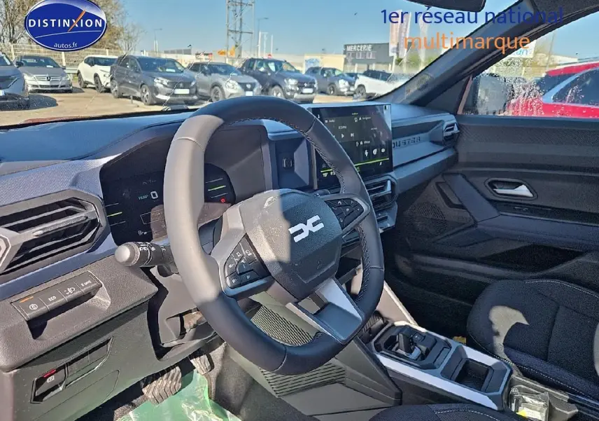 Intérieur du Dacia Duster 2025, vue côté conducteur sur le volant multifonction et l'écran tactile moderne.