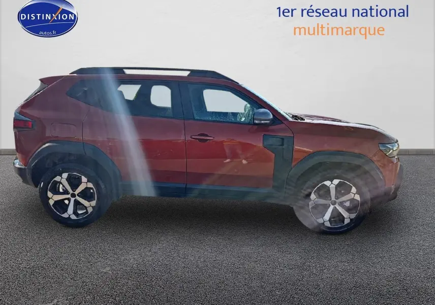 Profil droit du Dacia Duster 2025 brun terracotta avec jantes alu et barres de toit noires visibles