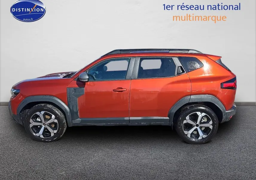 Profil côté gauche du Dacia Duster 2025 brun terracotta avec barres de toit et jantes alu distinctives.