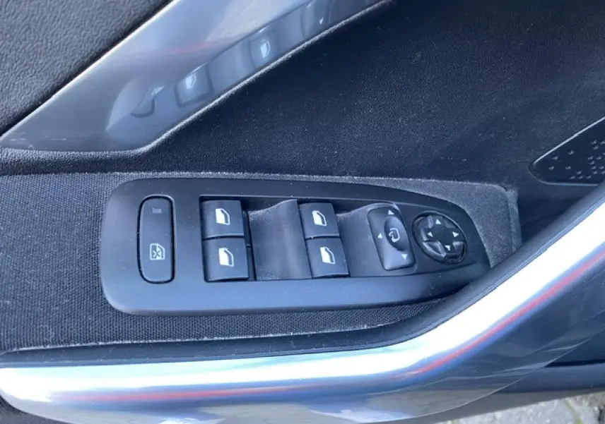 Vue rapprochée des commandes des vitres et rétroviseurs sur la porte côté conducteur du Peugeot 2008 noir 2019.