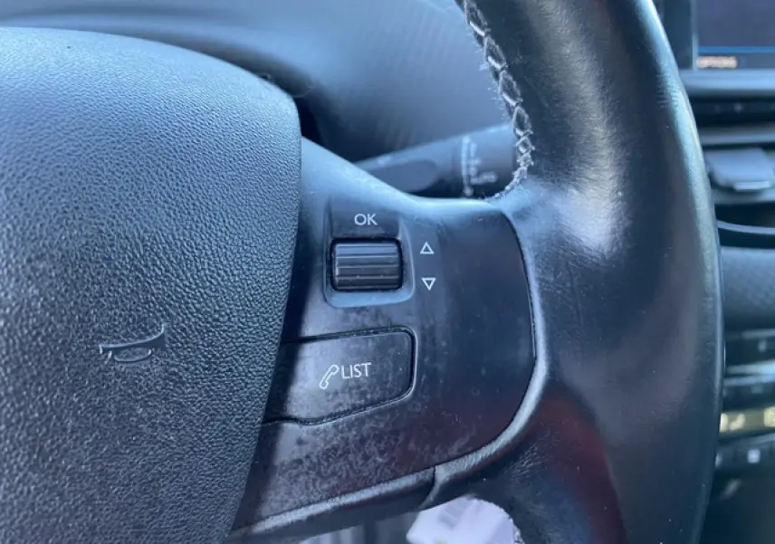 Gros plan sur les commandes gauche du volant noir du Peugeot 2008 2019, avec bouton OK et fonction liste d'appels.