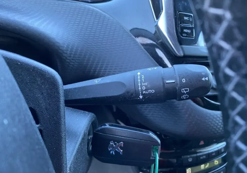 Gros plan sur la commande d'essuie-glace et la clé Peugeot dans l'habitacle noir du 2008 Diesel 2019.