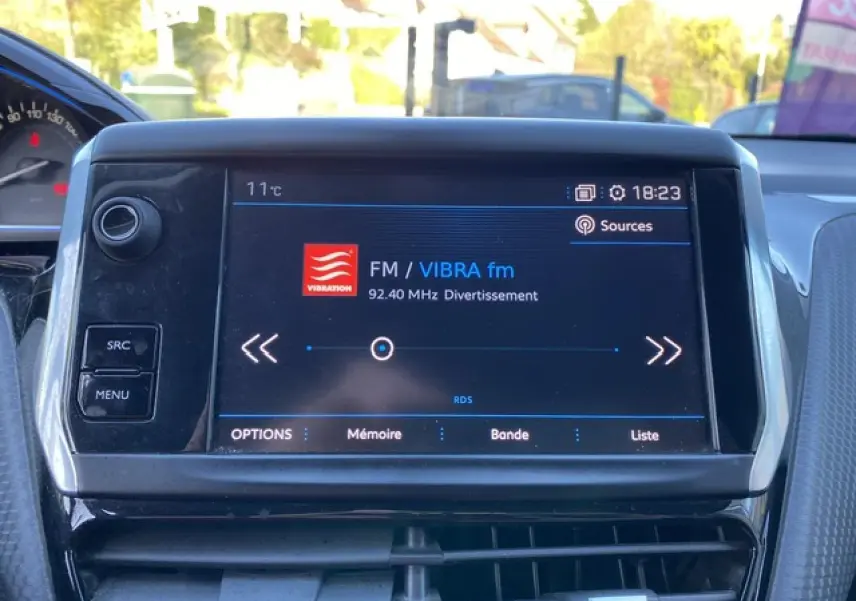 Écran tactile central du tableau de bord du Peugeot 2008 2019 affichant la radio FM VIBRA fm à 18h23.