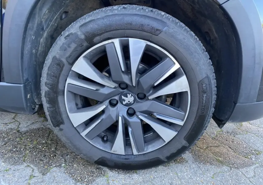 Gros plan sur la jante aluminium 16 pouces diamantée Aquila gris Storm du côté avant droit d'un Peugeot 2008 noir 2019.