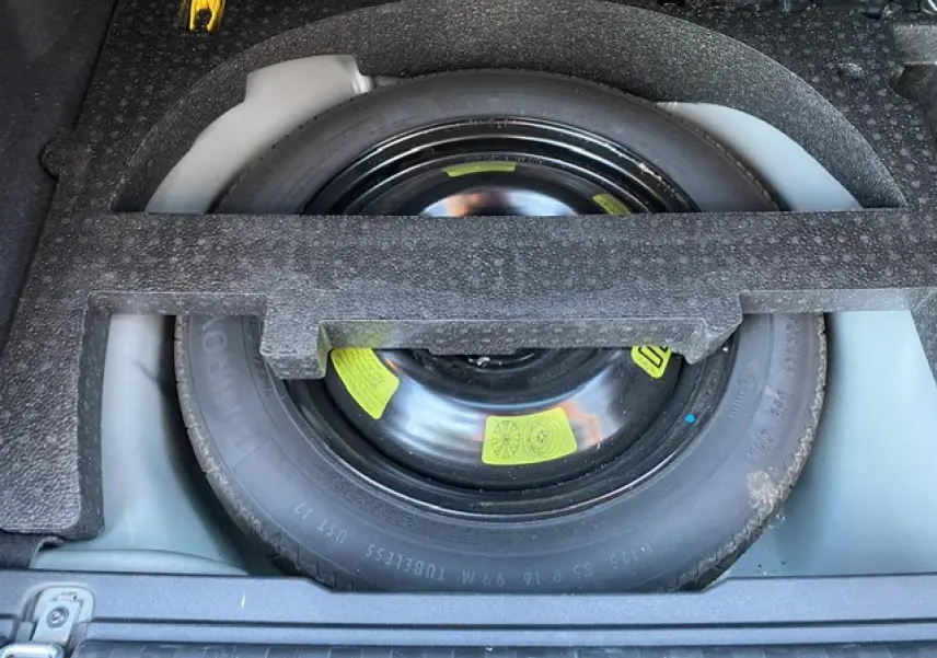 Roue de secours noire logée dans le coffre d'un Peugeot 2008 2019 finition Allure diesel noir.