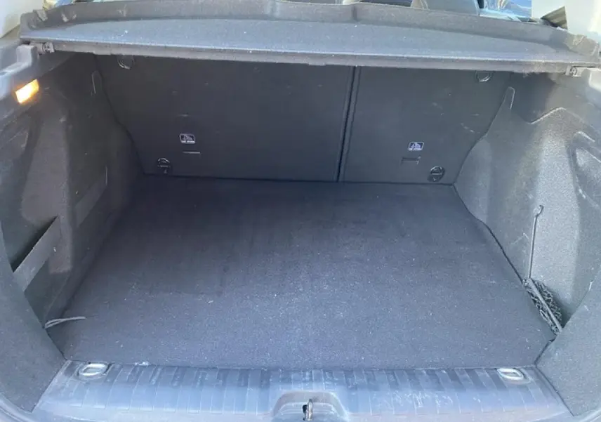 Coffre spacieux et propre du Peugeot 2008 noir, vue intérieure arrière avec cache-bagages relevé.