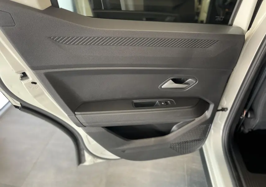 Porte arrière gauche ouverte du Dacia Duster beige 2025, montrant la garniture intérieure noire avec commandes de fenêtre.
