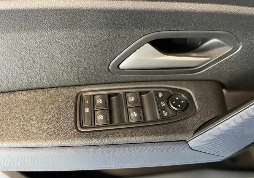 Poignée intérieure et panneau de commandes des vitres côté gauche en tissu Denim Bleu sur Dacia Duster 2025.