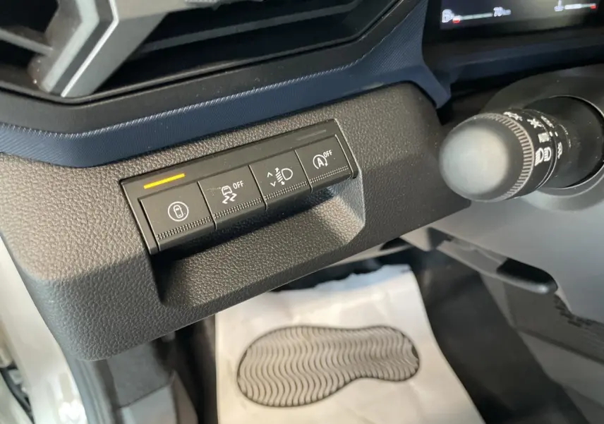 Gros plan sur les commandes de sécurité à gauche du volant dans l'habitacle du Dacia Duster beige 2025.