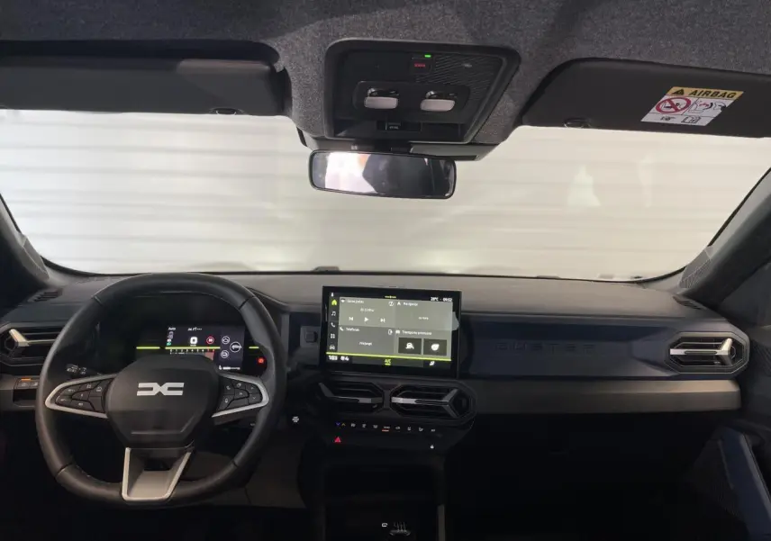 Vue frontale de l'intérieur du Dacia Duster beige 2025, avec tableau de bord digital et écran tactile central.
